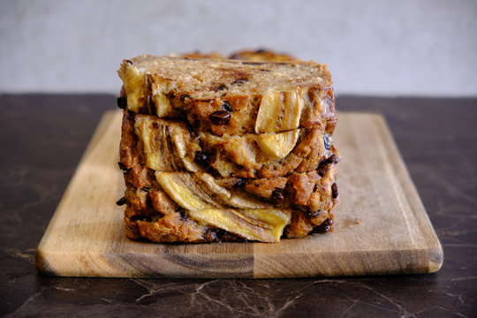 Homemade healthy banana bread served on a wooden board, black marble surface