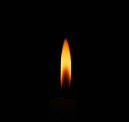 Lit flame of a candle on dark background 