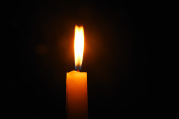 Lit flame of a candle on dark background 