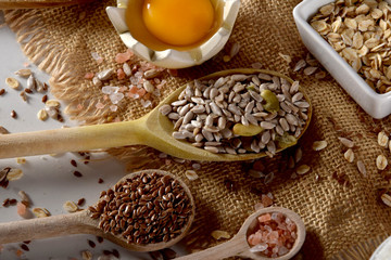 raw chicken egg yolk, wooden spoons and various containers full of Himalayan salt, linseed, sunflower seeds and oatmeal