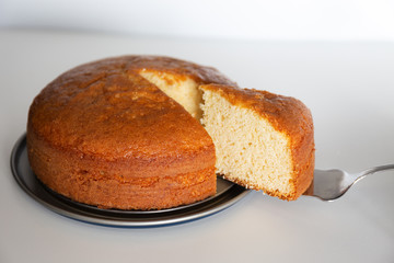 Delicious homemade sponge cake, with a portion on a white background