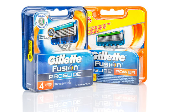Moscow, Russia - January 23, 2020: Gillette Fusion Proglide razor blades in blue and orange blister packs isolated on white background with shadow and reflection on the glossy surface