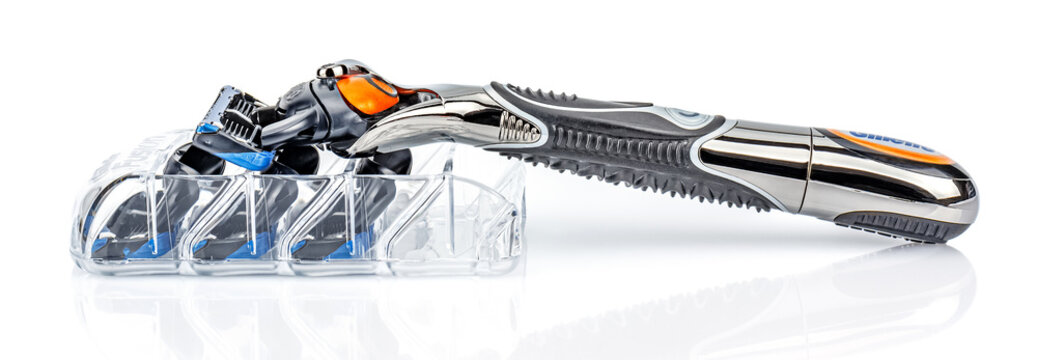 Moscow, Russia - January 23, 2020: Gillette Fusion Proglide Power battery razor handle with attached blade lying on transparent plastic holder of razor blades on white background with reflection