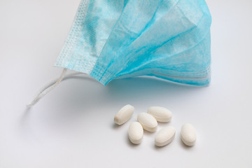 Medical mask and white pills on a white background. Worldwide coronavirus pandemic concept