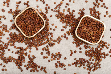 Raw gray peas in wooden bowls on sack cloth. Legumes bean seed. Organic healthy diet food. View from above.
