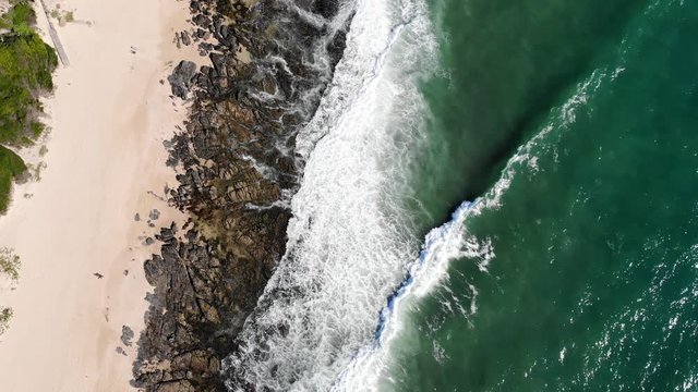 Aerial top down view of powerful nature waves crashing on beach shore rocks, Supertubes