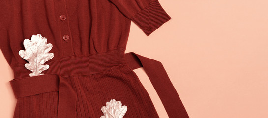 Fashion sweater terracotta color, cozy autumn female clothing decorated oak leaves on pastel pink background with copy space. Autumn flat lay, banner.