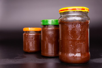 Jars with plum jam on a black background.