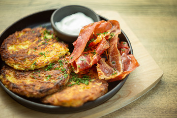 Potato pancakes with cooked bacon, sour cream