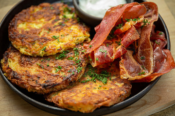 Potato pancakes with cooked bacon, sour cream