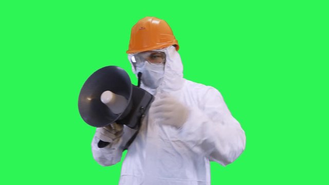 A man in a helmet and a protective suit speaks in a shout waving his hands giving out commands.Green screen background.