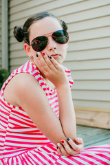 Young girl sitting on a front porch wearing sunglasses