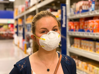 Blonde woman wears a respirator when shopping for food in retail and wholesale during the Corona pandemic