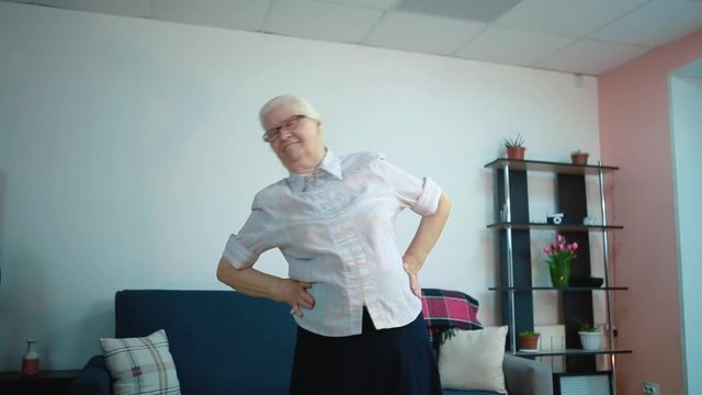 Does exercises at homeAn elderly woman does exercises while in the room
