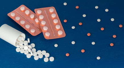 Scattered white and brown tablets in blisters on a blue background. Pharmaceuticals for the treatment of coronavirus. Copy space