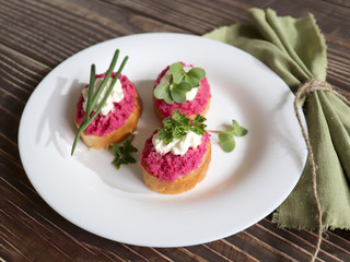 Beautiful sandwiches with pink and white sauce, fresh herbs on a white plate and wooden background and a napkin.