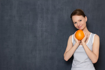 Portrait of happy woman holding fresh grapefruit in hands and smiling