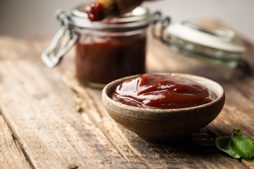 Barbecue sauce in a saucer with basting brush over rustic barn wood table with copy space.