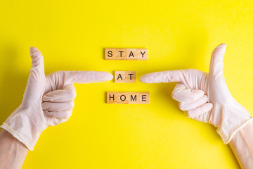 Stay at home hands in rubber gloves quarantine self-isolation on a yellow background