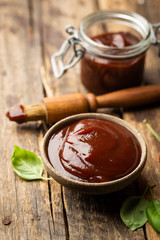 Barbecue sauce in a saucer with basting brush over rustic barn wood table with copy space.