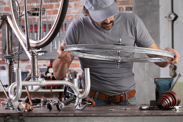 man repair the vintage bicycle in garage workshop on the workbench with tools, diy concept
