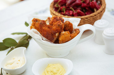 Fried chicken . Mayonnaise inside a bowl . A bowl of white ceramic salt and pepper. Red Dry Pepper in Traditional Basket .
