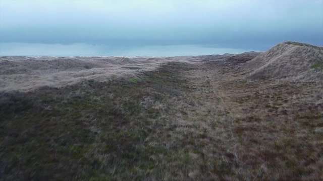 Fly over dunes with rain clouds in the background