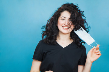 Beautiful happy black haired woman taking off medical antiviral mask.