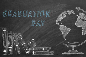 Lettering GRADUATION DAY, rotating globe and school books are drawn with chalk on a blackboard