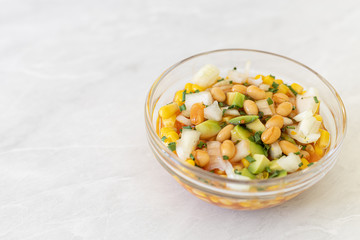 Salad with sliced avocado onions and canned corn in the bowl with copy space
