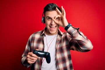 Fototapeta na wymiar Young handsome caucasian gamer man playing video games using console joystick with happy face smiling doing ok sign with hand on eye looking through fingers