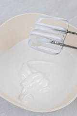 Fototapeta na wymiar White whipped cream in the bowl with mixer above