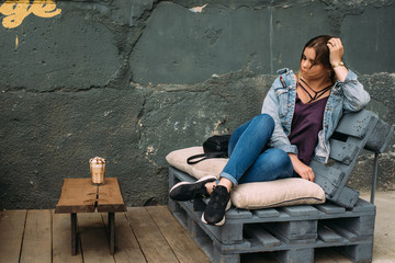 A young woman on the summer terrace of an eco-style coffee shop