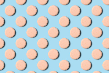 Seamless pattern of pharmaceutical pills or vitamins on a blue background. Orange pills on a blue background.