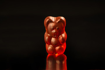 Close-up of a dark red gummy bear on a black background