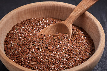 Flax seeds and a wooden spoon with bowl on a dark table. Healthy food and drink concept. Top View.