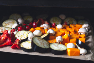 Healthy Detox Dinner from different vegetables such as aubergine, red pepper, cherry tomatoes, butternut squash, mushrooms. Slices of Raw vegetables prepared for the roasting, simple family meal