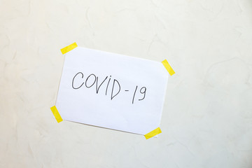 The inscription covid-19 on a sheet glued to the wall. The concept of self-isolation. Coronavirus, stop the spread of infection. 2019-ncov.