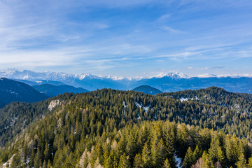 Aerial view of huge valley of the mountains of Italy, Trentino, green meadows, Slopes with green spruce trees, Dolomites on background