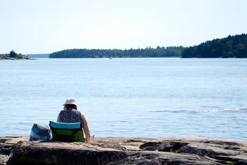 Foto op Canvas a woman alone sunbathes on the beach of the Baltic sea in Finland © Mariia Lomarainen