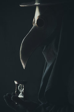 Plague doctor holds hourglass. Toned and noise art image