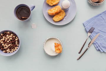 Breakfast with fried croutons, yogurt and black tea on light wooden background. Summer country food.