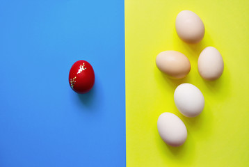 White Easter eggs on blue and yellow background with one red egg .