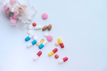 pills spilling from a container on white background 