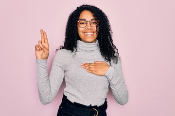 Young african american woman wearing turtleneck sweater and glasses over pink background smiling...