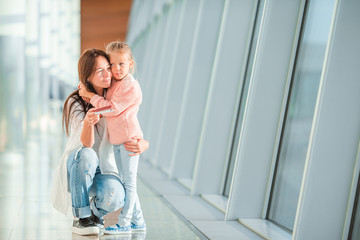 Happy mum and little girl with boarding pass at airport