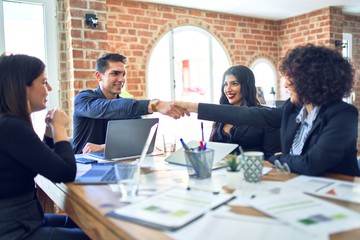 Group of business workers smiling happy and confident. Working together with smile on face shaking hands for agreement at the office