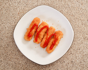 Fish sticks or fingers on white plate. Top down view.