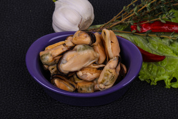 Pickled mussels in the bowl served pepper, garlic and salad