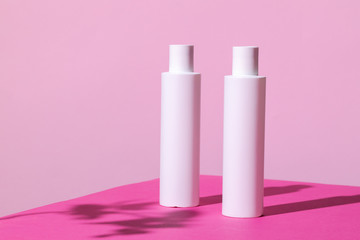Skincare products containers on bright pink background close up